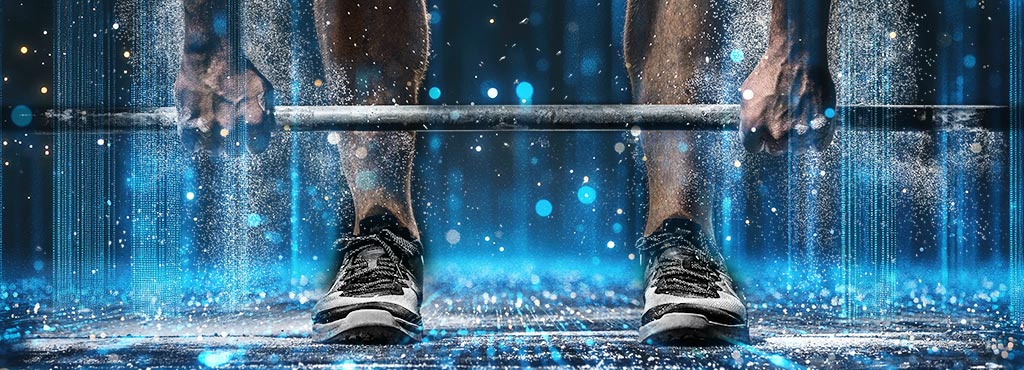 A close-up of a person’s hands and feet preparing to lift a barbell, with chalk dust and blue particles floating in the air, creating a dynamic, energetic atmosphere.