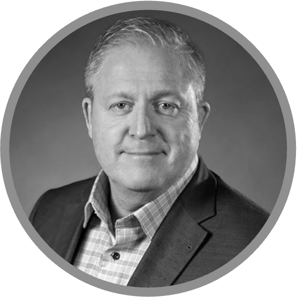 Black and white portrait of a middle-aged man with short, light hair, wearing a checked shirt and a suit jacket, looking at the camera with a slight smile. Meet Uniti Wholesale’s dedicated professional in this striking image.
