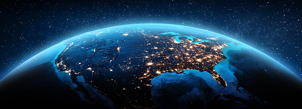 A view of North America from space at night, showing city lights illuminating the continent beneath a dark, star-filled sky.